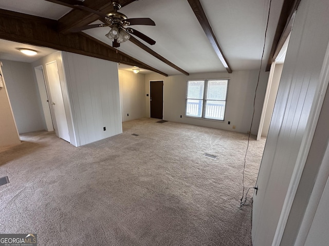 unfurnished living room with lofted ceiling with beams, light colored carpet, ceiling fan, and wood walls