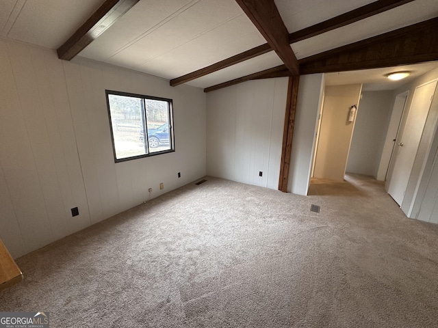 carpeted spare room with lofted ceiling with beams and wood walls