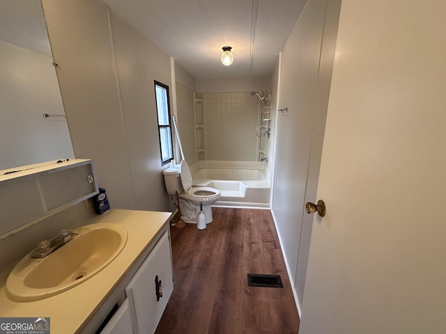 full bathroom featuring vanity, tiled shower / bath combo, toilet, and hardwood / wood-style flooring