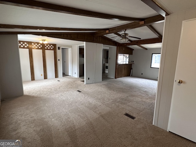 unfurnished living room featuring carpet, vaulted ceiling with beams, and ceiling fan