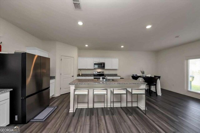 kitchen with appliances with stainless steel finishes, a center island with sink, dark hardwood / wood-style flooring, and white cabinets