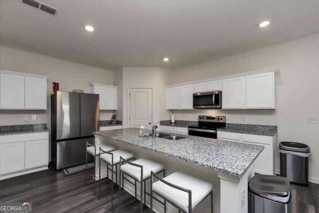 kitchen with sink, white cabinetry, stainless steel appliances, dark hardwood / wood-style floors, and a kitchen breakfast bar