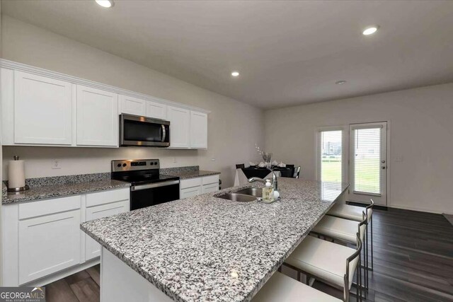 kitchen featuring stainless steel appliances, white cabinets, a kitchen island with sink, and sink