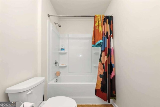 bathroom featuring shower / tub combo and toilet