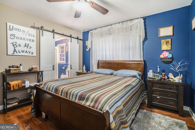 bedroom featuring ceiling fan, dark hardwood / wood-style floors, and a barn door