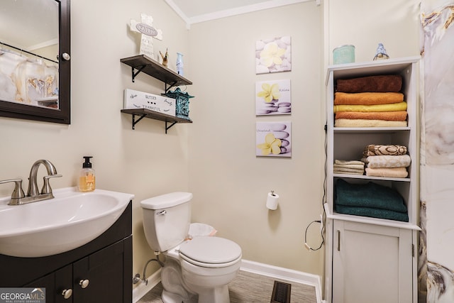 bathroom featuring wood-type flooring, ornamental molding, vanity, and toilet