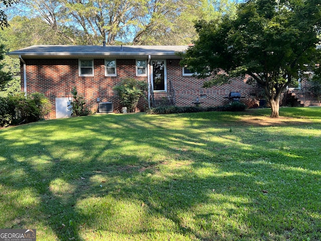 single story home with cooling unit and a front yard