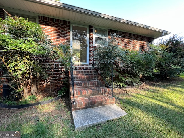 view of exterior entry featuring a lawn