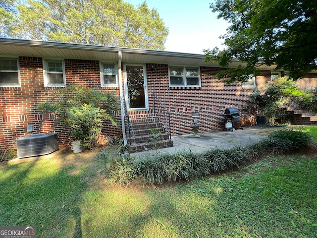 view of front facade with a front yard, cooling unit, and a patio area