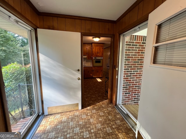 entryway with crown molding and wood walls