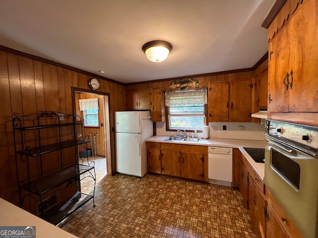 kitchen with ornamental molding, white appliances, wooden walls, and sink