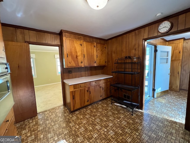 kitchen with crown molding, wooden walls, and stainless steel oven