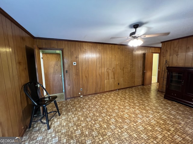 unfurnished room with ornamental molding, wood walls, and ceiling fan