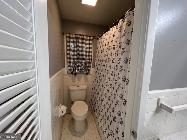 bathroom with tile walls, tile patterned flooring, curtained shower, and toilet