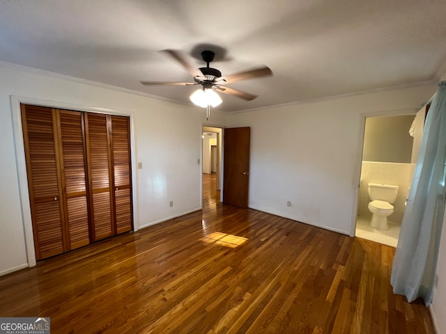 unfurnished bedroom featuring a closet, ensuite bath, ceiling fan, and dark hardwood / wood-style floors