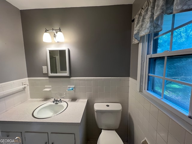 bathroom featuring vanity, tile walls, plenty of natural light, and toilet