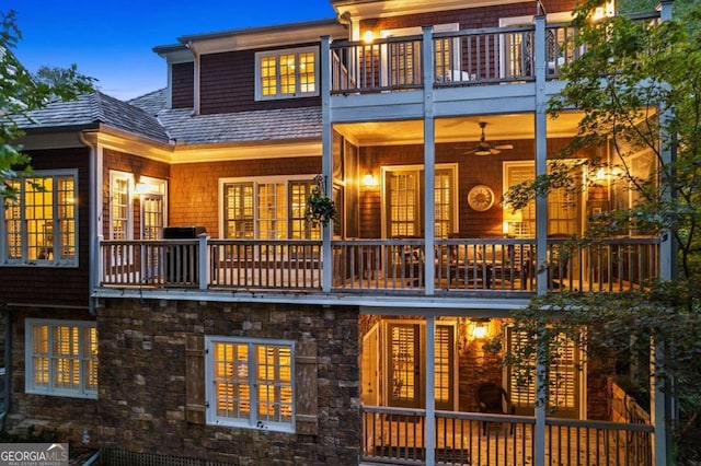 back house at dusk with a balcony and ceiling fan