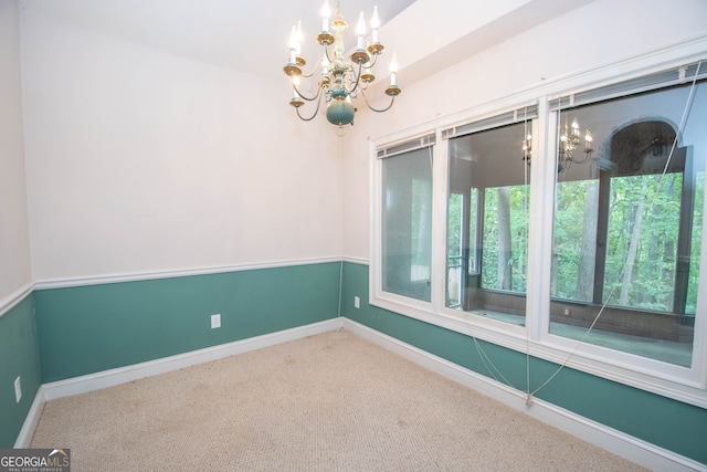 carpeted empty room featuring a chandelier