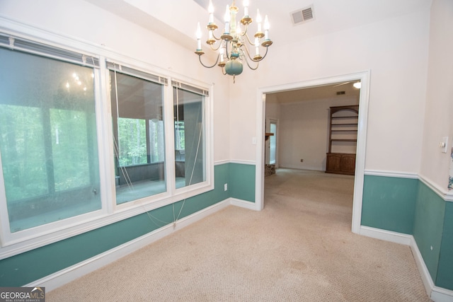 carpeted empty room featuring a notable chandelier