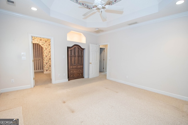 unfurnished bedroom featuring a raised ceiling, ensuite bath, and ornamental molding