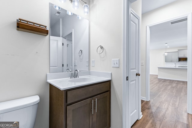 bathroom with toilet, hardwood / wood-style flooring, and vanity