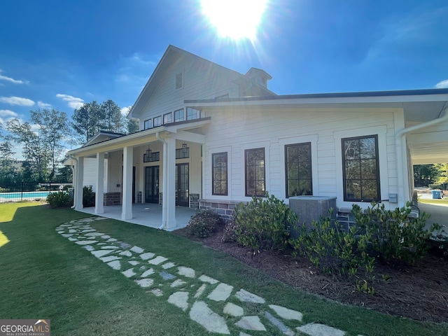 back of property featuring ceiling fan, cooling unit, a swimming pool, a patio, and a lawn