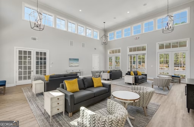 living room with light hardwood / wood-style flooring, a high ceiling, and a wealth of natural light