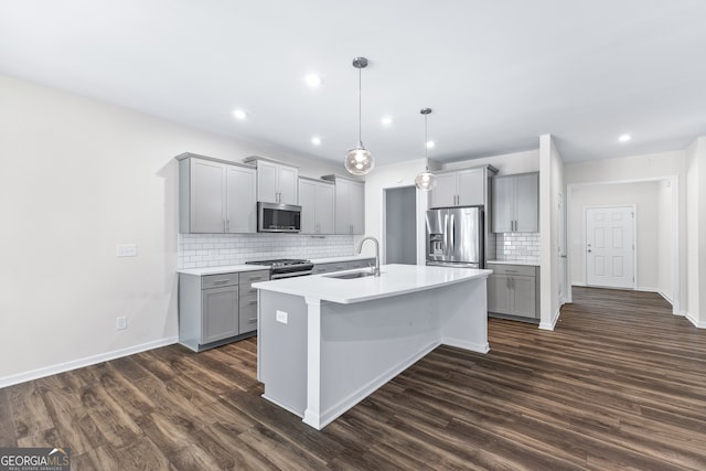 kitchen featuring appliances with stainless steel finishes, sink, pendant lighting, and dark hardwood / wood-style flooring