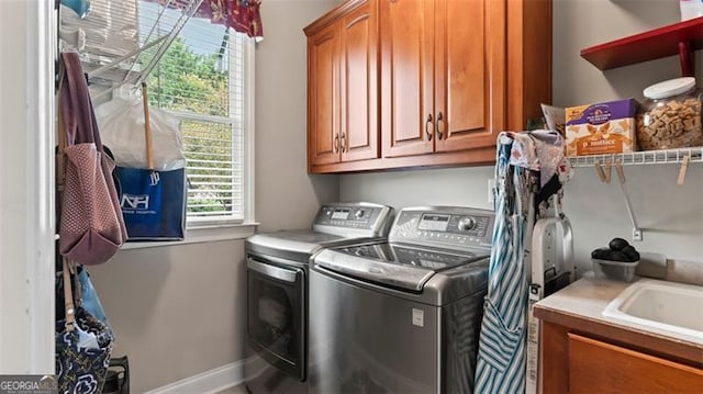 clothes washing area featuring sink, washing machine and clothes dryer, and cabinets