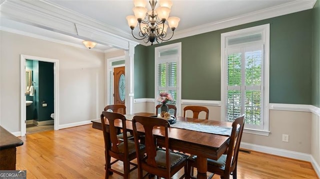 dining room with an inviting chandelier, light wood-type flooring, crown molding, and a healthy amount of sunlight