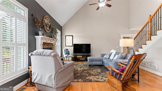 living room featuring a healthy amount of sunlight, ceiling fan, light hardwood / wood-style flooring, and high vaulted ceiling