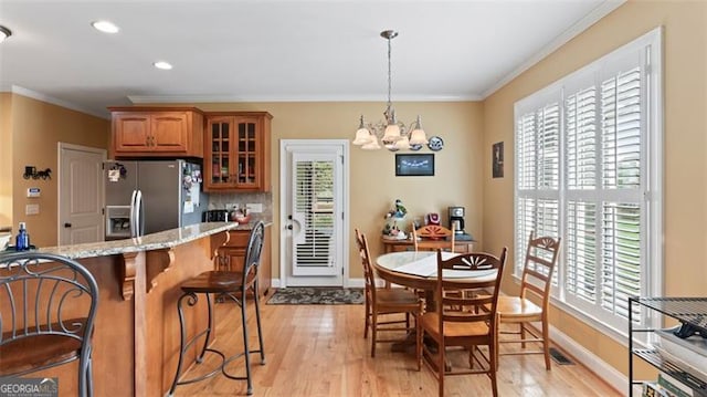 kitchen featuring pendant lighting, light stone countertops, light hardwood / wood-style floors, and stainless steel fridge with ice dispenser