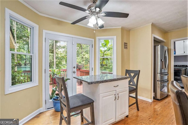 interior space featuring a wealth of natural light, stainless steel refrigerator with ice dispenser, black range, and white cabinetry