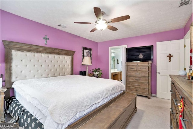 bedroom with light carpet, connected bathroom, ceiling fan, and a textured ceiling