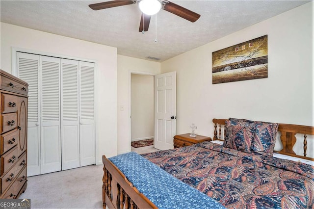 carpeted bedroom featuring a closet, ceiling fan, and a textured ceiling