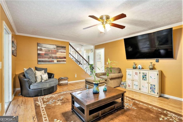 living room with a textured ceiling, hardwood / wood-style flooring, ceiling fan, and crown molding