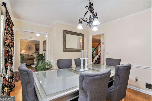 dining area featuring ornamental molding, a chandelier, and hardwood / wood-style floors