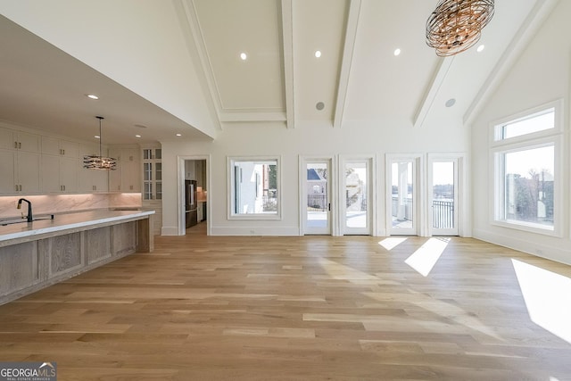 interior space featuring sink, plenty of natural light, high vaulted ceiling, and light wood-type flooring