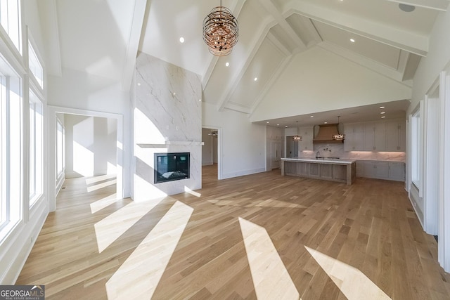 unfurnished living room with beamed ceiling, high vaulted ceiling, and light hardwood / wood-style flooring