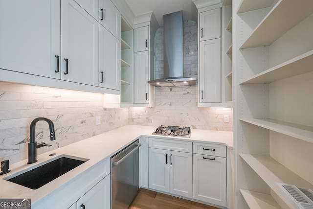 kitchen featuring white cabinets, wall chimney exhaust hood, sink, and appliances with stainless steel finishes