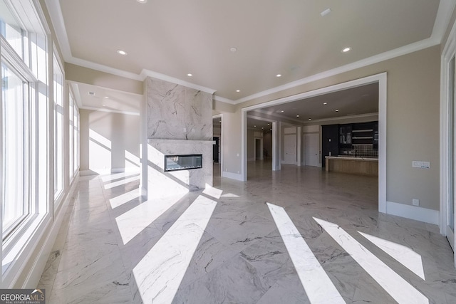 unfurnished living room with a high end fireplace, a wealth of natural light, and ornamental molding