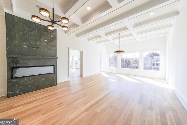 unfurnished living room with coffered ceiling, beamed ceiling, a fireplace, tile walls, and hardwood / wood-style flooring