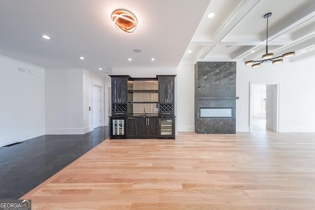 unfurnished living room with beam ceiling, crown molding, beverage cooler, and light hardwood / wood-style flooring