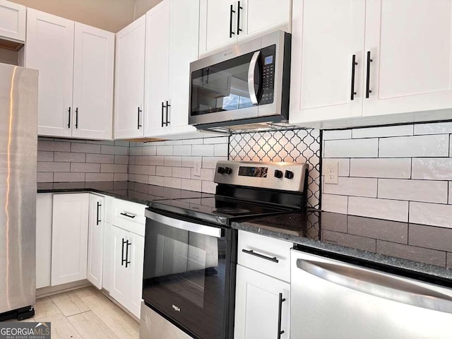 kitchen with decorative backsplash, white cabinetry, appliances with stainless steel finishes, and dark stone counters