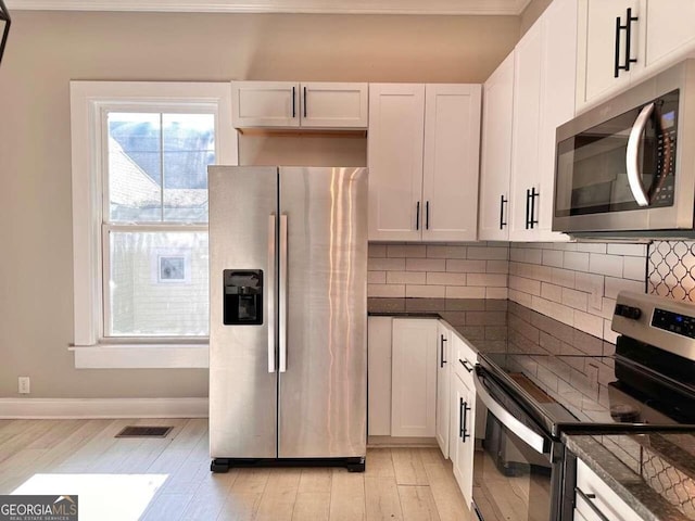 kitchen with appliances with stainless steel finishes, white cabinetry, and light hardwood / wood-style flooring