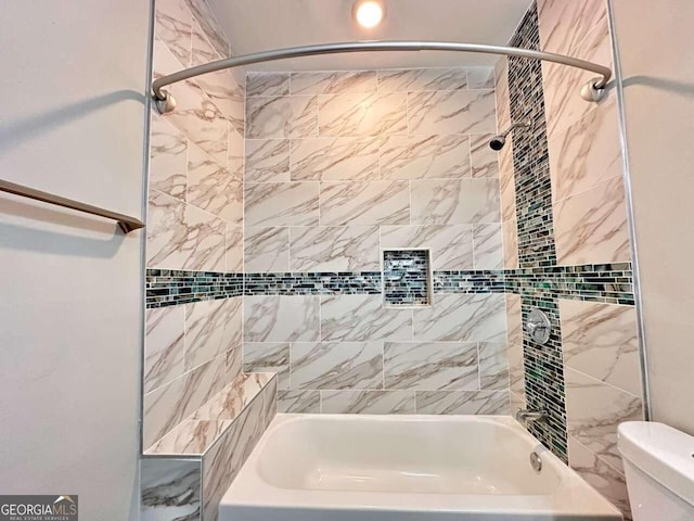 bathroom featuring tiled shower / bath combo and toilet