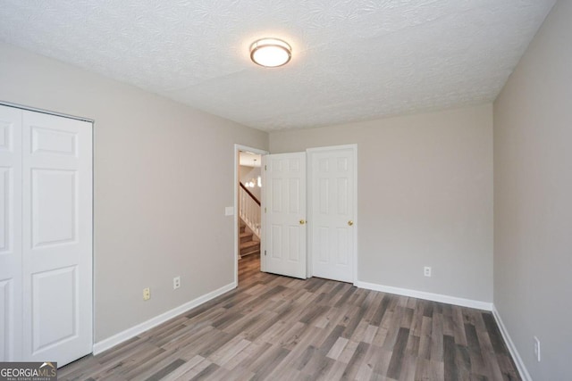 unfurnished bedroom with hardwood / wood-style flooring, a closet, and a textured ceiling