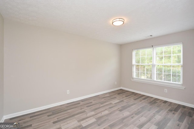 empty room with a textured ceiling and hardwood / wood-style flooring