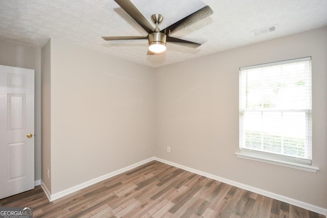 unfurnished room with ceiling fan, hardwood / wood-style flooring, and a textured ceiling