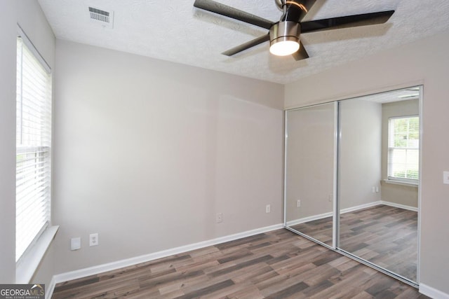 unfurnished bedroom with a closet, ceiling fan, dark hardwood / wood-style floors, and a textured ceiling